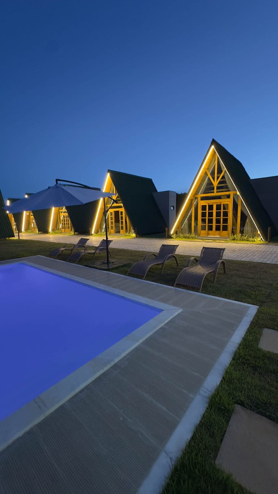 Chalés A-Frame de madeira iluminados à noite com piscina - Wood Bahia